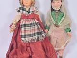 Deux poupées représentant des femmes vêtues de costumes d'époque se tiennent côte à côte.