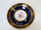 une assiette bleue et dorée ornée d'un oiseau
