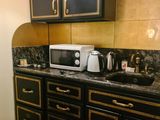 une cuisine noire et dorée avec un micro-ondes posé sur le plan de travail