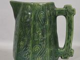 a green pitcher that has a handle on it