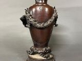 a brown vase with a dragon on it on a table