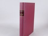 un vieux livre à la couverture rose posé sur une surface blanche