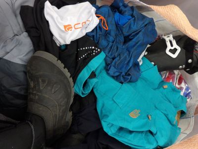 une valise remplie de vêtements et de chaussures posée sur un lit