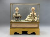 deux poupées dans une vitrine posée sur une table