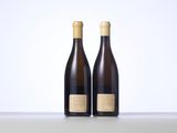 two bottles of wine sitting on top of a table next to each other