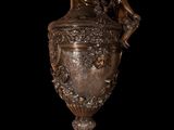 a bronze vase with a man on it on a black background