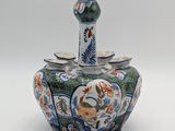 a small vase with a bird on it on a white surface