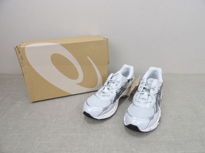 La paire de chaussures de course blanches et noires se trouve à côté d'une boîte
