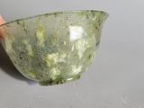someone is holding a small bowl with a green substance inside of it