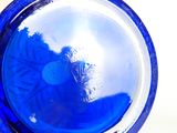 un gros plan d'un vase en verre bleu dans lequel se reflète une personne