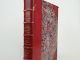 un vieux livre à la couverture rouge posé sur une surface blanche