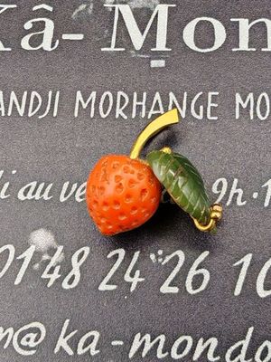 une petite fraise posée sur une plaque sur laquelle se trouve une feuille verte