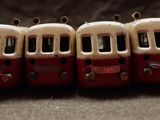 four miniature red and white buses lined up on a table