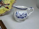 a white and blue pitcher and a plate on a table