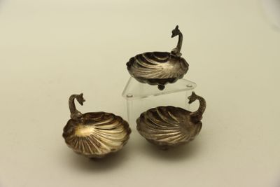 deux objets plaqués argent posés sur une surface blanche, sur fond blanc