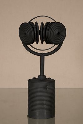 une sculpture noire représentant un casque audio posé sur une canette