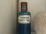 une bouteille bleue de « Veget's Pully » posée sur une étagère à côté d'un corail blanc