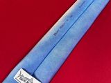 a blue tie with a label on it on a red surface
