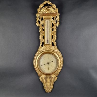 a gold clock hanging on the wall on a black background