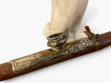 a statue of a bird sitting on top of a wooden stick