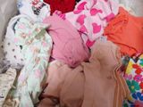 a pile of baby clothes in a basket on a bed