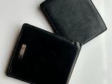 two black leather wallets sitting next to each other on a white surface