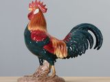 a figurine of a rooster on a wooden table