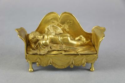 une figurine en or représentant une femme allongée sur un canapé