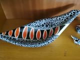 a black, orange and white bowl sitting on top of a wooden table