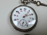 a silver pocket watch with a key attached to it