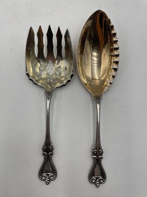 deux cuillères et une fourchette en argent sur une surface blanche