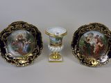 trois pièces de porcelaine décorées d'une peinture, posées sur une table
