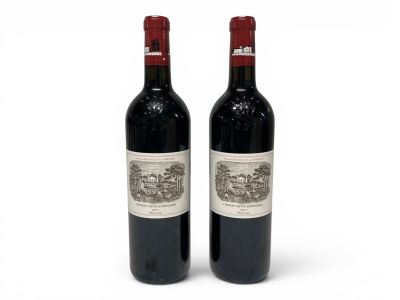 two bottles of red wine sitting next to each other on a white surface
