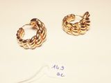 two pairs of gold hoop earrings on a white surface