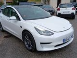 a white tesla model 3 parked in a parking lot