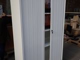 a tall white cabinet with a sliding door next to a pallet