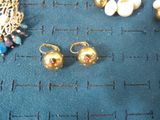 two pairs of earrings and a necklace on a blue surface