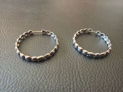 two silver hoop earrings on top of a leather surface