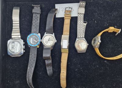 quatre montres différentes dans un écrin noir, posées sur un fond noir