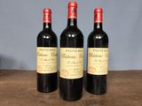 three bottles of red wine sitting on top of a wooden table
