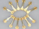 six gold spoons are arranged in a circle on a white surface