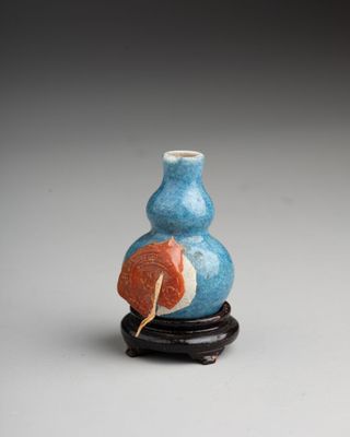 an image of a small blue vase with a leaf on it