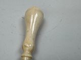 a wooden stick with a handle on a white surface
