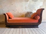 une chaise longue ornée de coussins orange, placée devant un mur