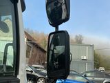 une voiture bleue garée sur un parking à côté d'un camion blanc