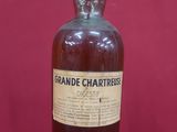 une vieille bouteille de brandy repose sur une surface rouge