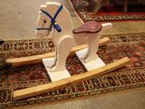 un cheval à bascule en bois posé sur un tapis posé à même le sol
