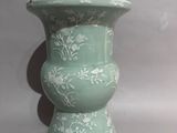 a green vase with white flowers on it