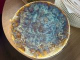 une pizza posée sur une table en bois, à côté d'une pile d'assiettes
