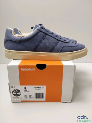 les baskets bleues sont posées sur une boîte, posée elle-même sur une surface blanche